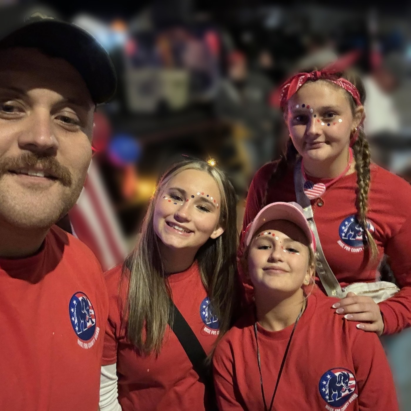 Cody Rose and his daughters in Rose for County Board shirts at a night parade.